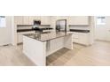 Modern kitchen with white cabinets, black countertops, stainless steel appliances, and a central island at 7185 Waterleaf Trl, Littleton, CO 80125