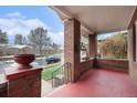 Inviting covered front porch with brick columns, a red painted floor, and views of the street at 3159 36Th Ave, Denver, CO 80211