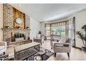 Bright living room featuring a cozy brick fireplace and large window allowing ample natural light at 2299 Ranch Dr, Westminster, CO 80234