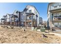 Attractive three-story townhome featuring gray and white tones and landscaping awaiting its final touches at 6910 Merseyside Ln, Castle Pines, CO 80108