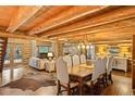 Elegant dining area with a wooden table, fireplace, hardwood floors, and a view into the living room and outdoor scenery at 34100 Woodland Dr, Evergreen, CO 80439