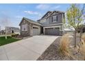 Beautiful two-story home featuring a stone facade, gray siding, a three-car garage and a large concrete driveway at 6802 S Uriah St, Aurora, CO 80016