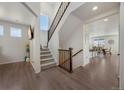 Bright and open foyer featuring hardwood floors, a staircase with wooden railings, and views into the kitchen area at 6802 S Uriah St, Aurora, CO 80016