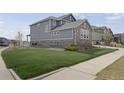 Well-maintained side yard with lush green grass and stone accents on the home at 6802 S Uriah St, Aurora, CO 80016