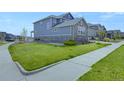 A lush lawn wraps around this two-story home, complemented by light blue siding and tasteful stone accents at 6802 S Uriah St, Aurora, CO 80016