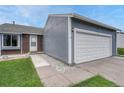 Exterior view of a two car garage with a gray exterior, white garage door and concrete walkway at 19140 E Milan Cir, Aurora, CO 80013