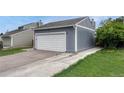 Exterior of a two car garage showcasing the gray exterior, white garage door and long concrete driveway at 19140 E Milan Cir, Aurora, CO 80013