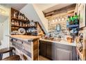 Basement bar with wood accents, brick, shelves, sink, and custom lighting at 330 N Wagonwheel Trl, Castle Rock, CO 80104