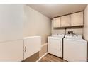 Functional laundry room with washer, dryer, cabinets, and modern wood-look floors at 330 N Wagonwheel Trl, Castle Rock, CO 80104