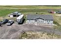 Aerial view of a gray single-story home, RV, detached garage, and parked trucks at 11809 Pass Me By Rd, Strasburg, CO 80136
