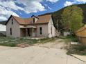 Exterior view of a charming home with a quaint front porch, greenery, and mountains in the background at 219 Colorado Blvd, Idaho Springs, CO 80452