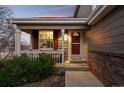 Inviting front porch with brick accents and a cozy seating area at 1271 Berganot Trl, Castle Pines, CO 80108