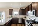This kitchen features dark cabinets, granite countertops, stainless steel appliances, and wood-look flooring at 7232 Shavano Ave, Frederick, CO 80504
