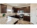 A modern kitchen with stainless steel appliances, dark wood cabinets and granite countertops at 7232 Shavano Ave, Frederick, CO 80504