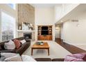 Spacious living room featuring a brick fireplace, high ceilings, and a view of the upper level loft at 9556 Kemper Dr, Lone Tree, CO 80124