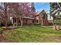 Charming two-story brick home with a lush front lawn and flowering tree at 239 Ash St, Denver, CO 80220