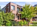 Modern brick house with a balcony, a well-manicured yard, and mature trees, offering privacy and curb appeal at 1833 E Jewell Ave, Denver, CO 80210