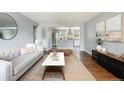 Sunlit living room featuring a modern sofa, wood floors and an open layout leading into a kitchen area at 8240 Grandview Ave, Arvada, CO 80002