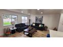 Bright living room with dark furniture, neutral paint, and new wooden floors at 6521 Zinnia St, Arvada, CO 80004