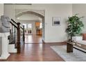 Welcoming foyer with brick archway, hardwood floors, stairs with wrought iron railing, and view of the kitchen at 21455 E 44Th Ave, Denver, CO 80249