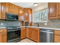 Well-equipped kitchen with wooden cabinetry, stainless steel appliances, and mosaic tile backsplash at 3195 S Kalispell Ct, Aurora, CO 80013