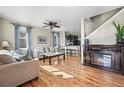 Cozy living room with hardwood floors, a fireplace, comfortable seating, and an open view to the kitchen at 19603 E 63Rd Pl, Aurora, CO 80019