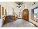 Elegant foyer featuring a grand staircase, stone floors, chandelier, and arched wood door at 850 E Radcliff Ave, Cherry Hills Village, CO 80113