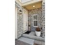 Home's entryway with stone facade, a white door with a small window, and a welcome mat at 10207 Xanadu St, Commerce City, CO 80022