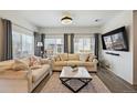 Bright living room featuring large windows, hardwood floors, neutral furniture, and modern decor at 10207 Xanadu St, Commerce City, CO 80022