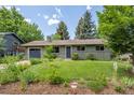 Charming single-story home with a lush green lawn, mature trees, and an attached garage at 3545 Cloverleaf Dr, Boulder, CO 80304