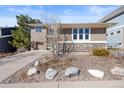 Traditional home boasting a well-manicured front yard with mature trees, rock accents, and classic brick siding at 3431 Fantasy Pl, Castle Rock, CO 80109