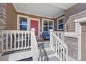 Inviting front porch featuring a cozy seating area and a charming red front door with decorative sidelights at 3431 Fantasy Pl, Castle Rock, CO 80109