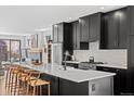 Modern kitchen boasts an oversized island with seating and sleek black cabinetry and stainless appliances at 4454 Utica St, Denver, CO 80212