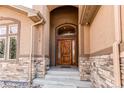 Inviting entryway features a grand arched doorway, stone accents, and a beautifully crafted wood door at 13970 Craig Way, Broomfield, CO 80020
