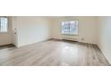 A well-lit room with light gray wood floors and a large window looking out onto the neighborhood at 1117 Elysian Field Dr # A, Lafayette, CO 80026