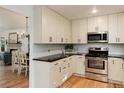 Bright kitchen showcases white cabinetry, black countertops, and stainless steel appliances at 8543 Redstone St, Highlands Ranch, CO 80126