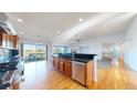 Gourmet kitchen with stainless steel appliances, black countertops, hardwood floors, and open access to deck at 14701 Yosemite St, Brighton, CO 80602