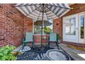 Cozy front porch with seating, umbrella, and brick facade offering a welcoming outdoor space at 2428 W 82Nd Pl # 1D, Westminster, CO 80031