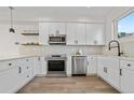 Modern kitchen featuring stainless steel appliances, white cabinets, and hardwood floors at 1907 W Elk Pl, Denver, CO 80211