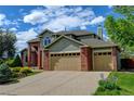 Attractive home featuring a three-car garage, brick accents, lush lawn, and blooming flower beds at 8286 W 108Th Pl, Broomfield, CO 80021