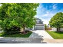 Traditional home with mature trees and landscaping, complimented by a spacious driveway leading to a garage at 5794 S Yakima Way, Aurora, CO 80015