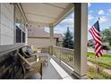 Inviting front porch with wicker furniture and American flag, perfect for relaxing at 23545 E Phillips Pl, Aurora, CO 80016