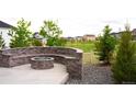 Beautiful backyard featuring a stone fire pit with seating, gravel beds, and lush greenery at 27655 E Geddes Pl, Aurora, CO 80016