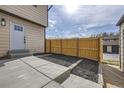 Backyard with a concrete patio, black mulch, and a wood fence under a partly cloudy sky at 11981 E Yale Ave, Aurora, CO 80014