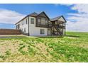 Two-story farmhouse with modern black and white design, a balcony, and a large backyard at 2400 Ventress Ct, Bennett, CO 80102