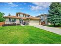 Well-maintained home with a lush green lawn, mature trees, and a convenient two-car garage at 2631 S Flanders Ct, Aurora, CO 80013