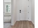 Bright hallway featuring sleek wood floors, a modern white door, and a glimpse of the living room at 39172 Clymer St, Elizabeth, CO 80107