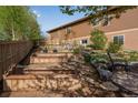 Landscaped backyard featuring multiple raised garden beds, stone steps, large boulders, and mature trees at 4000 Donnington Cir, Castle Rock, CO 80104