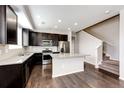 Modern kitchen with dark wood cabinets, stainless steel appliances, and granite countertops at 16075 E Elk Pl, Denver, CO 80239