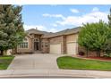 Charming home featuring a stone facade, manicured lawn, and three-car garage at 1251 Double Eagle Ct, Castle Rock, CO 80104